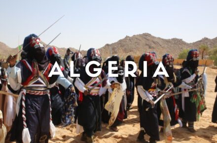 Guerrieri Tuareg con spade e abiti tradizionali in velluto durante la danza rituale del Festival della Sebiba a Djanet, Algeria.