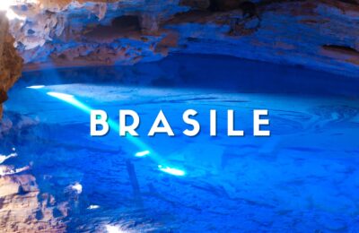 Grotta sotterranea con lago d'acqua cristallina dai riflessi blu intenso e formazioni rocciose nella Chapada Diamantina, Brasile.